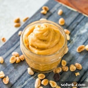 Peanut Butter Mousse with 4 Ingredients — Quick Creamy Dessert 12 A small, clear jar filled with peanut butter mousse on a serving tray surrounded by peanuts.