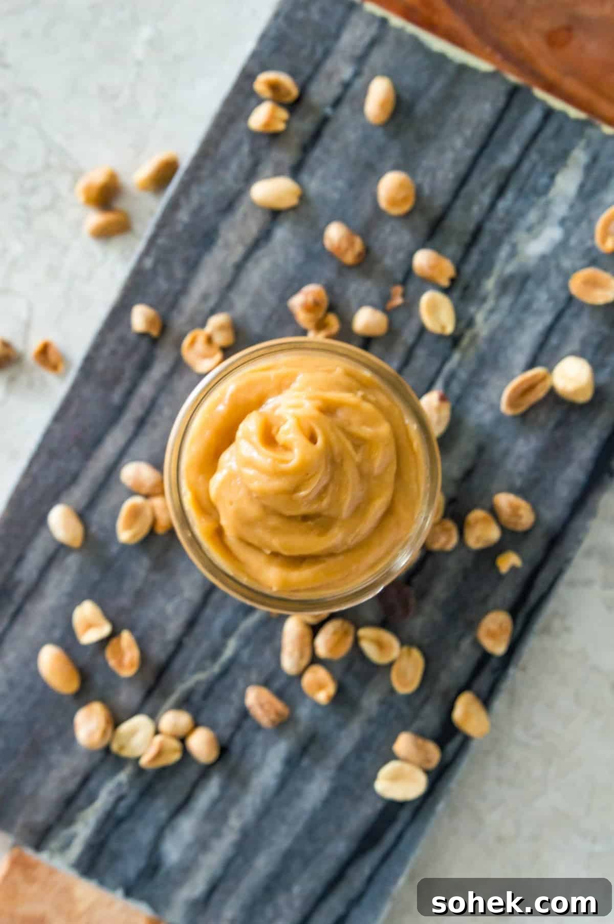 Peanut Butter Mousse with 4 Ingredients — Quick Creamy Dessert 7 A jar filled with peanut butter mousse on a serving tray surrounded by peanuts.