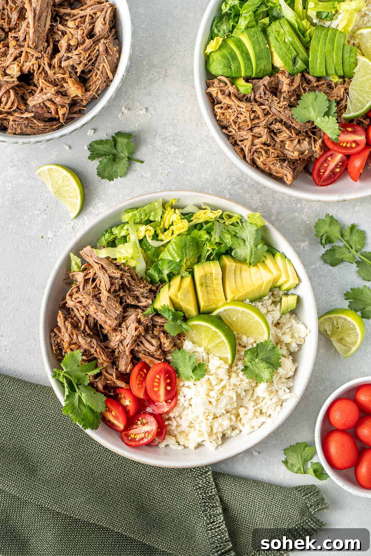 Whole30 beef burrito bowls served with avocado, tomato, lettuce and coriander. 