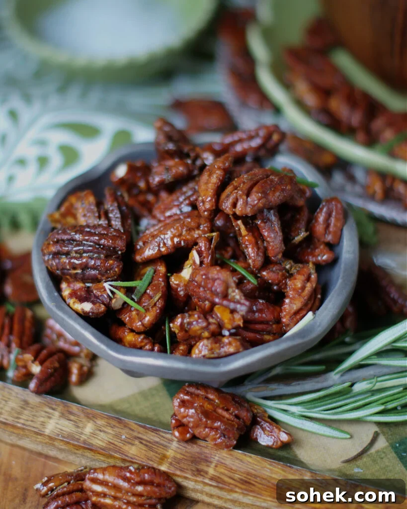 Rosemary Pecans in a pewter bowl with fresh rosemary and green cocktail napkins as a party appetizer idea.