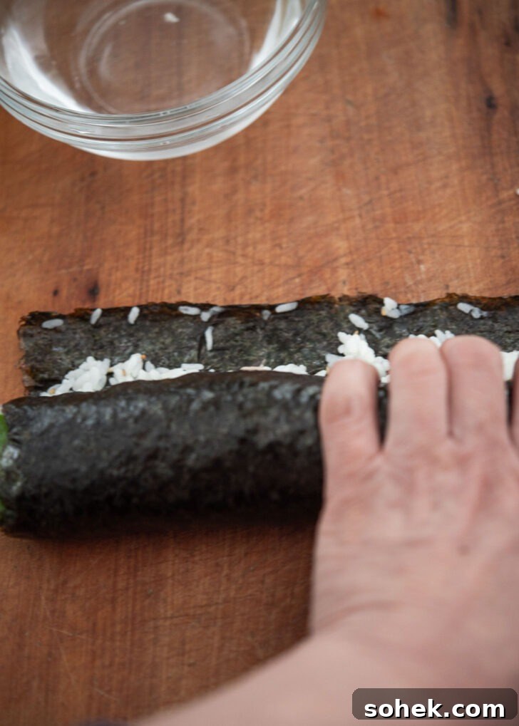 Hand rolling a Korean seaweed rice roll into shape

