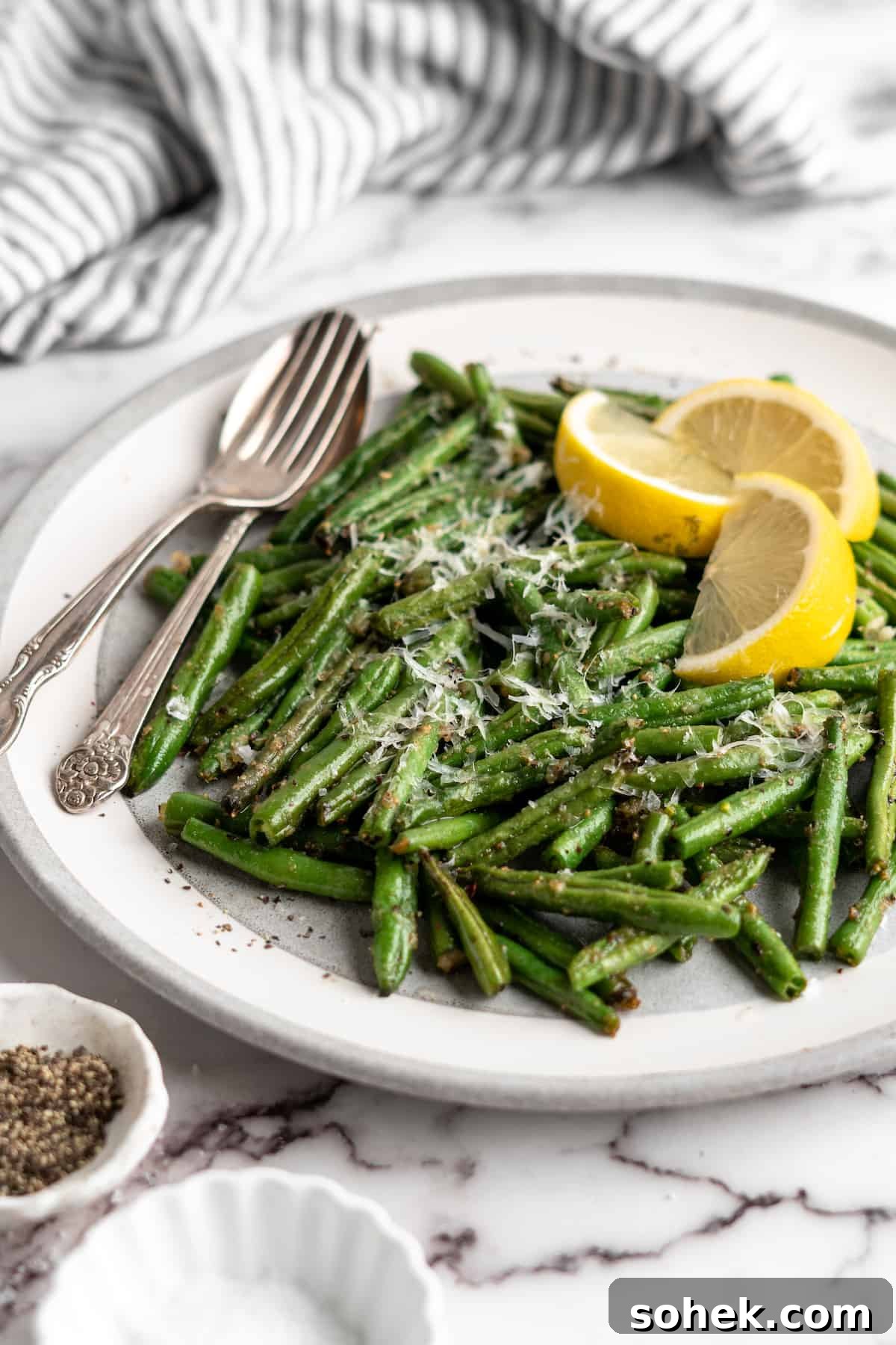 These air fryer green beans are seasoned to perfection and air fried until crispy for an easy side dish that goes with anything! Air fryer green beans on plate with spoon and fork.