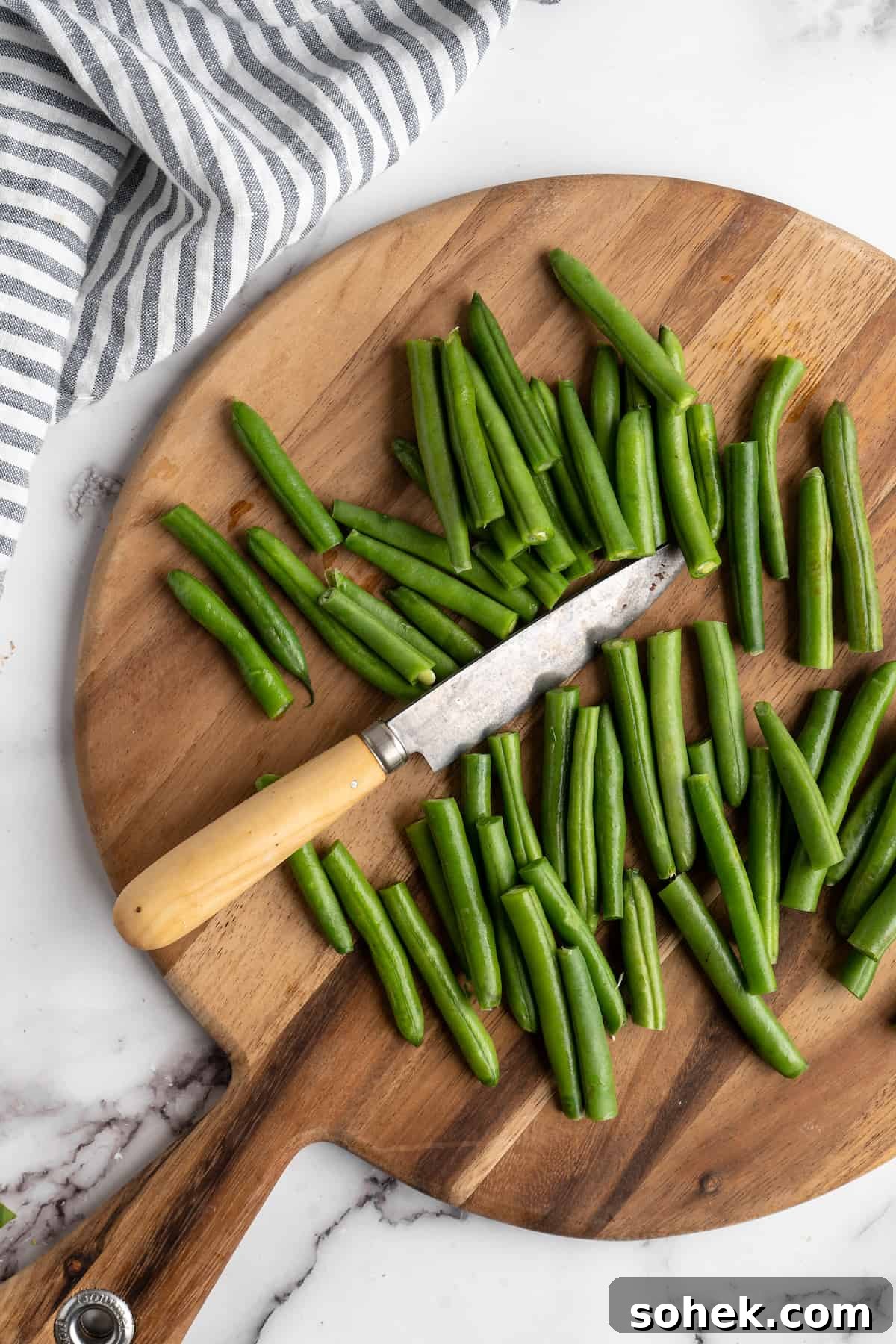 These air fryer green beans are seasoned to perfection and air fried until crispy for an easy side dish that goes with anything! Green beans on cutting board with knife.