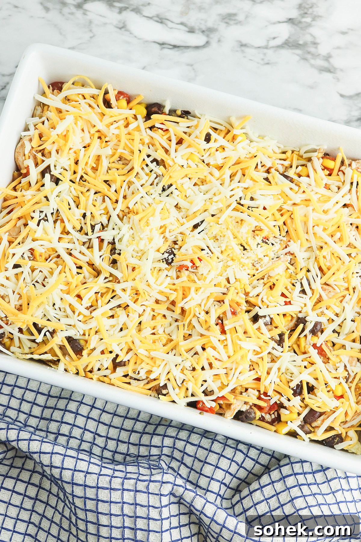 Mexican blend cheese added over Mexican chicken mixture in baking dish.
