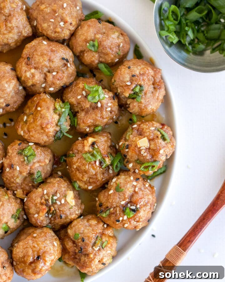 white plate of turkey meatballs topped with scallions and sesame seeds
