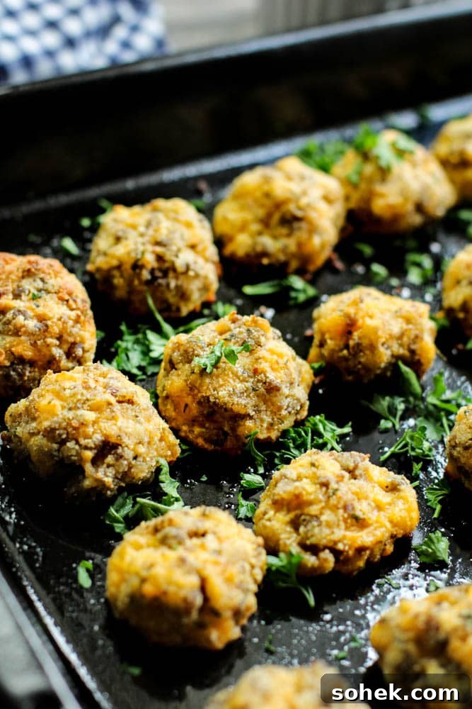 low carb sausage keto balls on a black baking tray with parsley garnished over it
