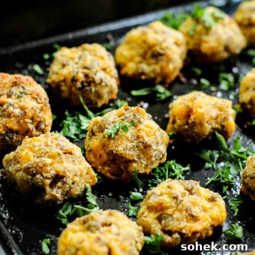 low carb sausage keto balls on a black baking tray with parsley garnished over it