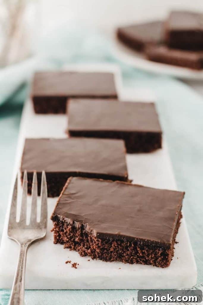 Gluten-Free Texas Sheet Cake Recipe: Moist Chocolate Sheet Cake 9 Four slices of gluten-free Texas sheet cake on a marble slab, one with a bite taken from the corner.