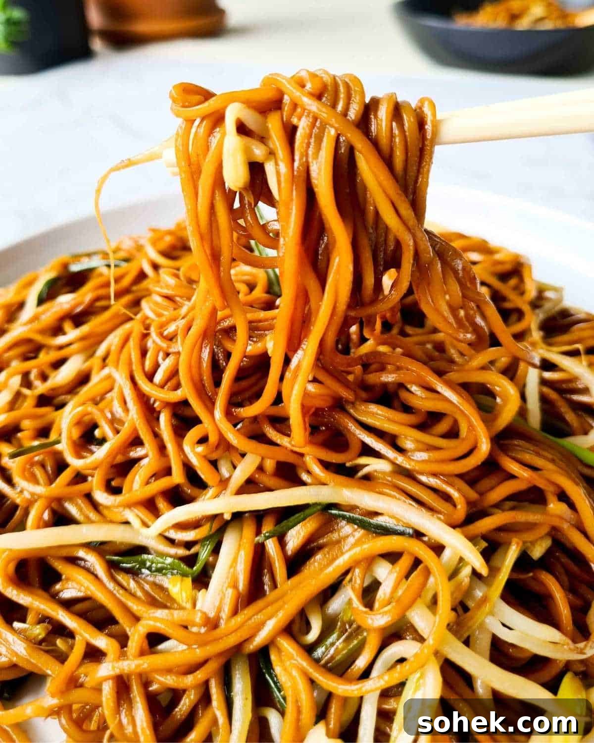 Noodles on a pair of chopsticks over a plate