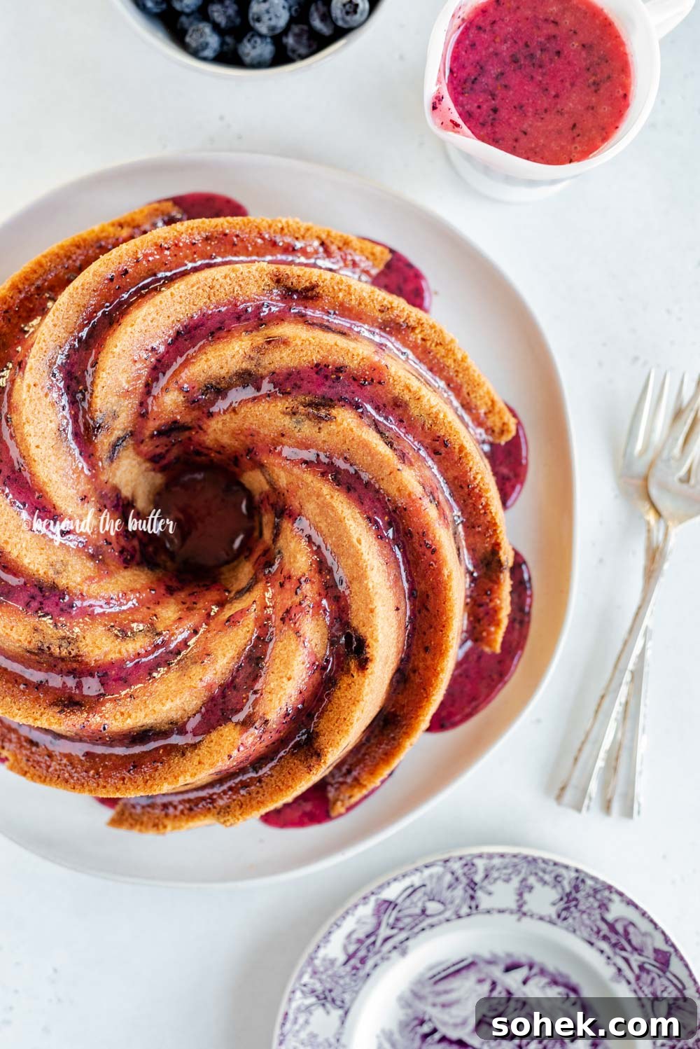 Overhead image of super easy blueberry bundt cake recipe with blueberry glaze drizzled over the top | All Images © Beyond the Butter, LLC