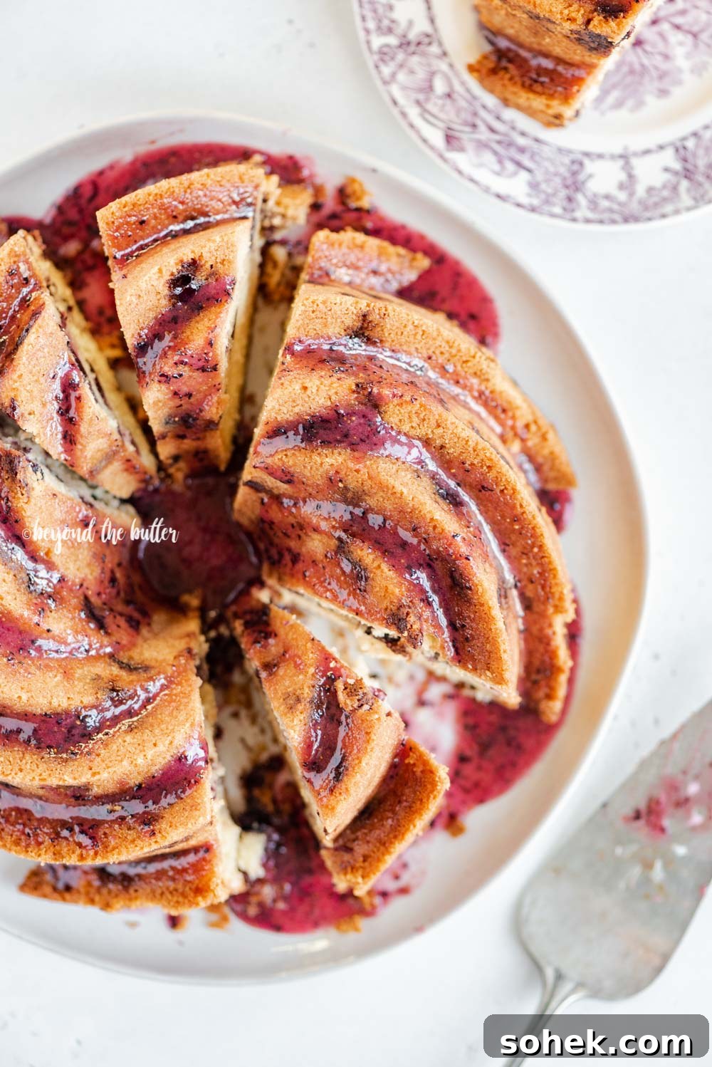 Overhead image of sliced blueberry bundt cake with blueberry glaze drizzled over the top | All Images © Beyond the Butter, LLC