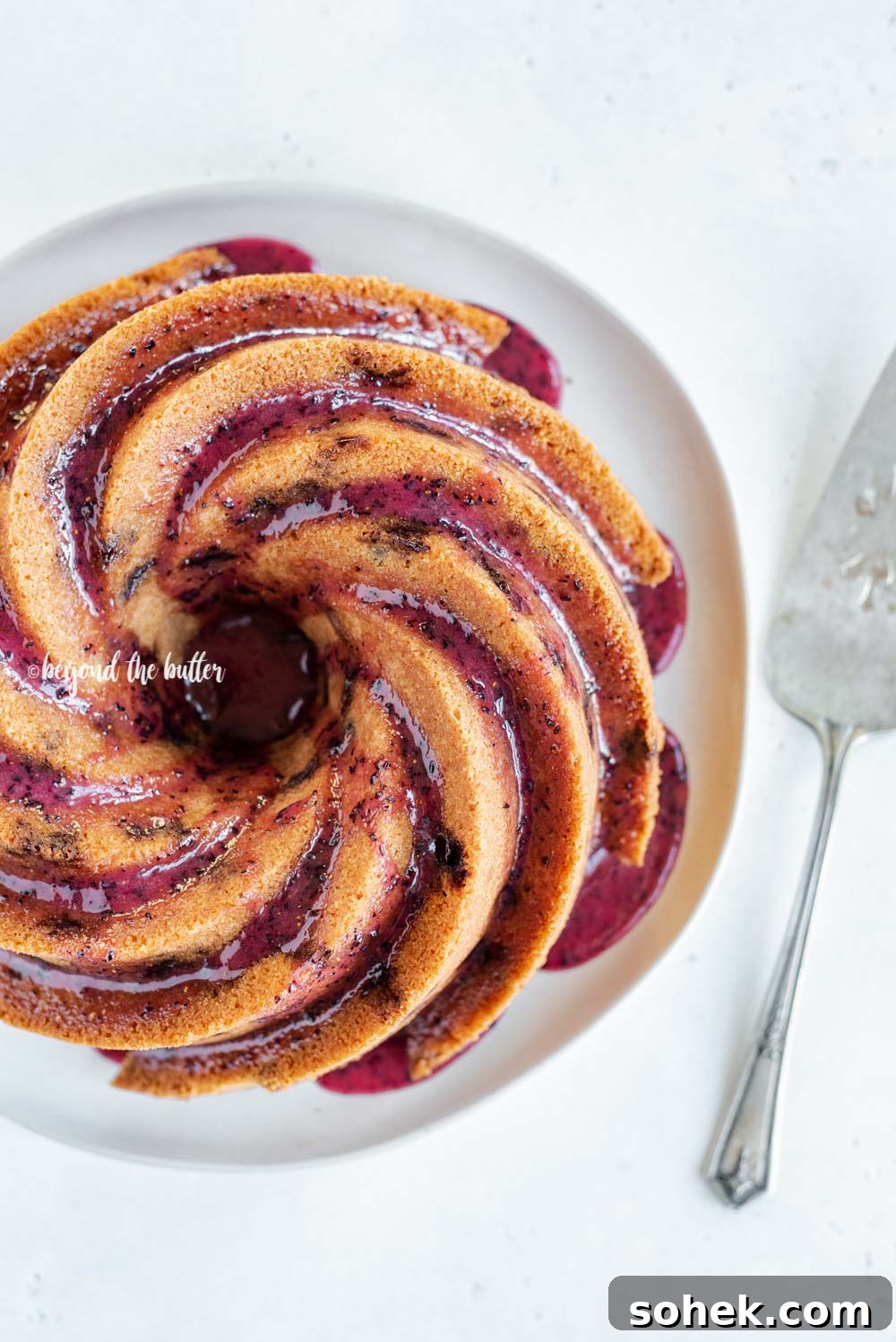 Overhead image of super easy blueberry bundt cake recipe with blueberry glaze drizzled over the top | All Images © Beyond the Butter, LLC