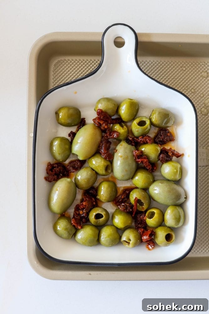 Mediterranean Baked Olives with Feta and Herbs 6 picture of olives and red pepper strips in a baking dish