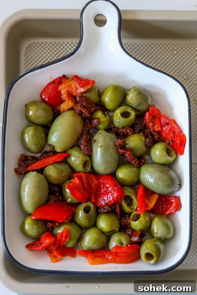 Mediterranean Baked Olives with Feta and Herbs 7 picture of olives red pepper and sun dried tomatoes in a baking dish
