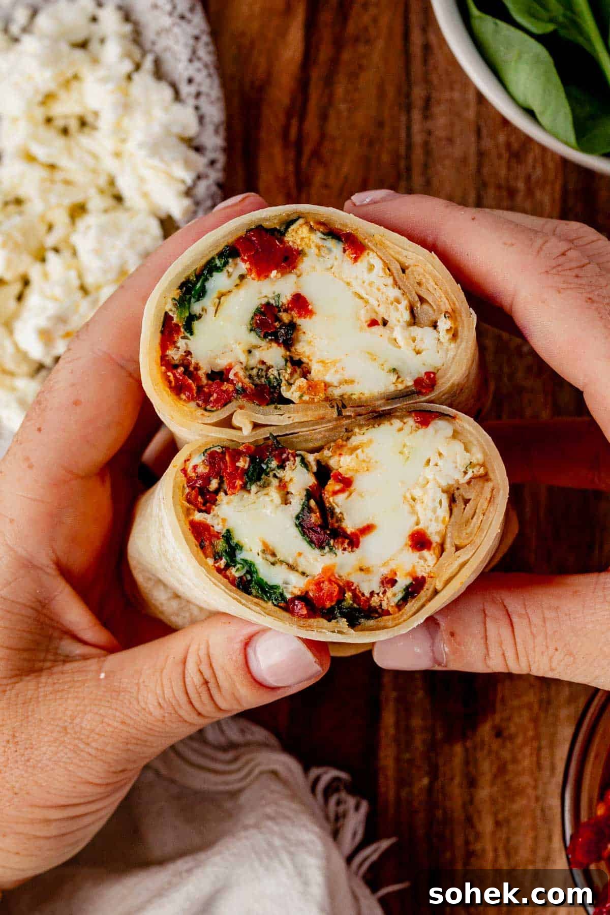 Spinach and Feta Egg White Wrap Recipe for Protein-Packed Breakfast 7 holding two halves of a spinach feta egg what wrap.