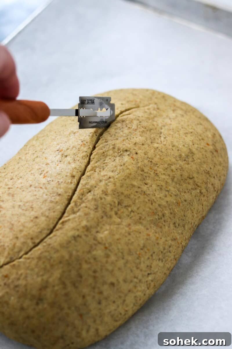 Person scoring the top of a loaf of bread.
