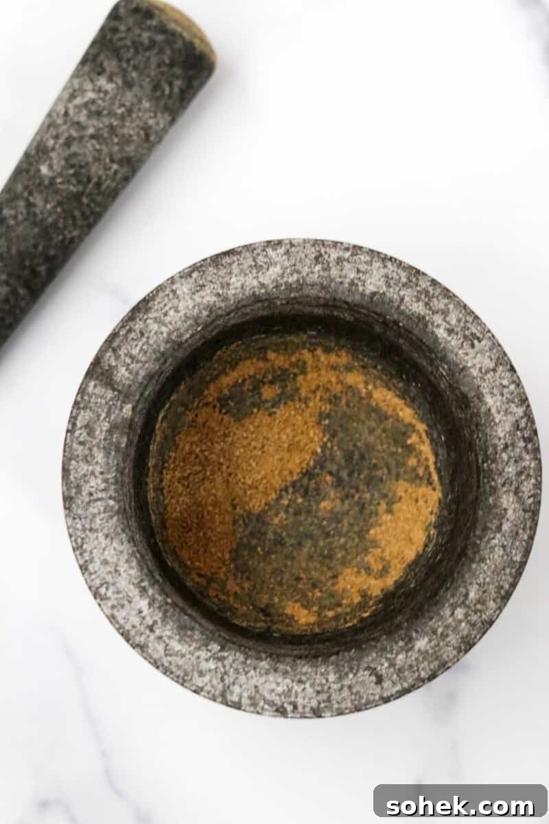 Spices in a mortar next to a pestle.