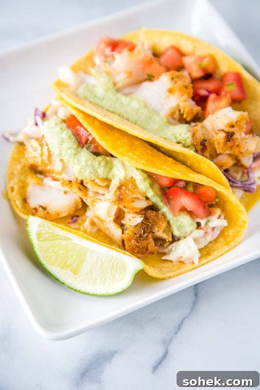 cod fish tacos with poblano cream sauce, pico de gallo and lime wedge