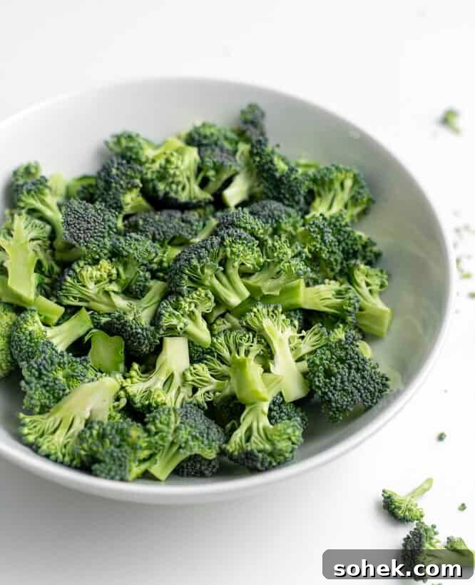 Cut up broccoli in a white bowl.