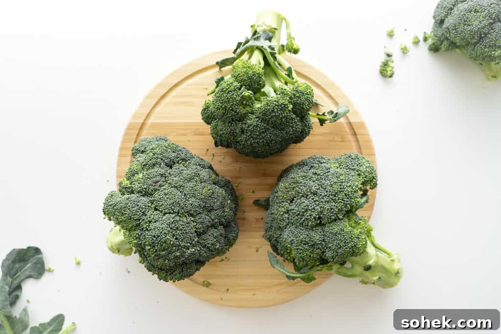 Three heads of broccoli on a cutting board.