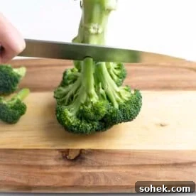 Knife cutting over broccoli stem.