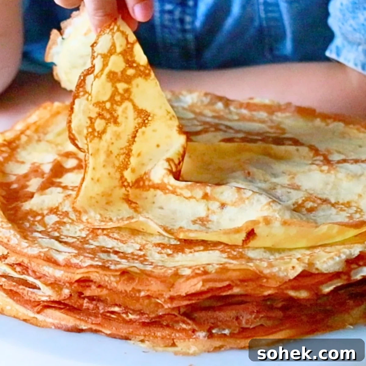 Classic French Crepes: Thin Pancake Recipe & Serving Ideas 3 taking a piece of homemade crepe by hand