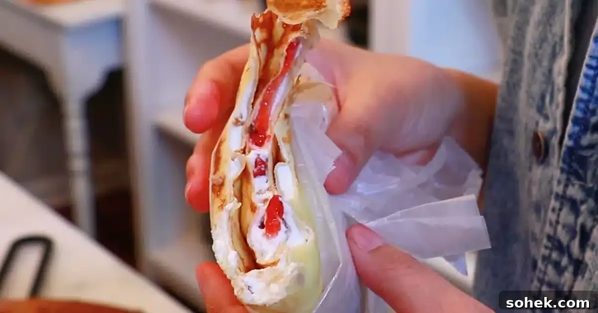 Classic French Crepes: Thin Pancake Recipe & Serving Ideas 6 eating a crepe filled with whipped cream and strawberries