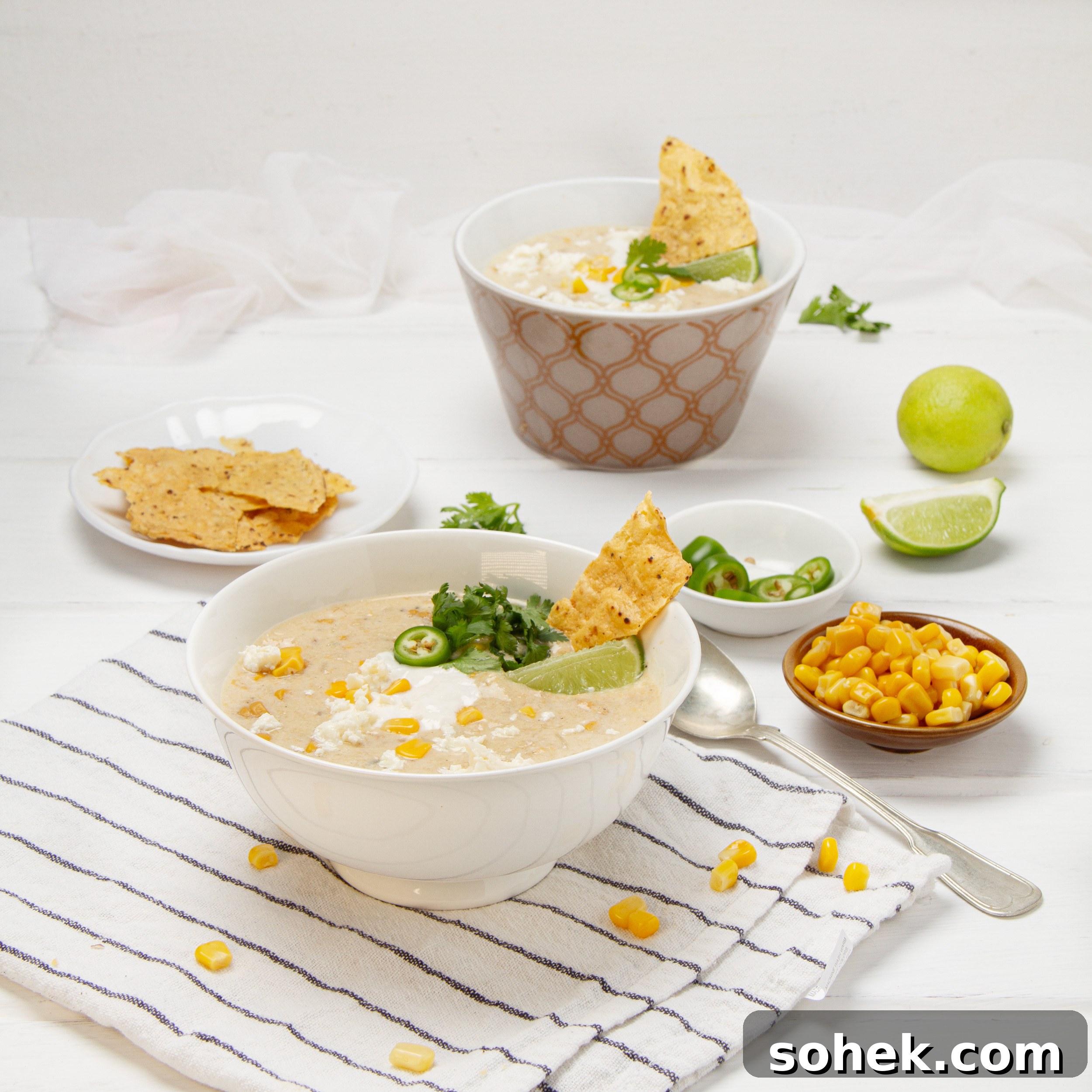 Mexican Street Corn Soup Recipe — Creamy Elote Chowder Tutorial 2 Creamy, authentic Mexican street corn soup in a bowl with chips, fresh lime wedges, and cilantro on the side.