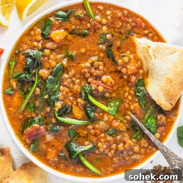 Lentil vegetable soup with spinach, a silver spoon and bread