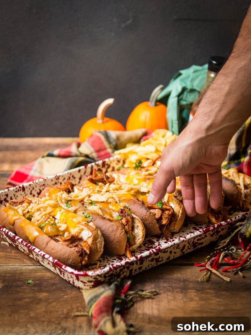 Tray of leftover smoked turkey sandwiches with melted cheese and arugula, hand reaching for one.
