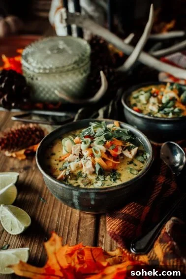 A bowl of creamy turkey soup garnished with green onions and herbs.