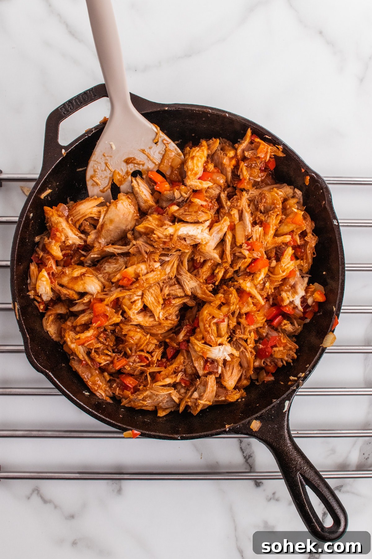 Cast-iron skillet of chopped smoked turkey mixed with onions and red pepper ready for sandwich filling.
