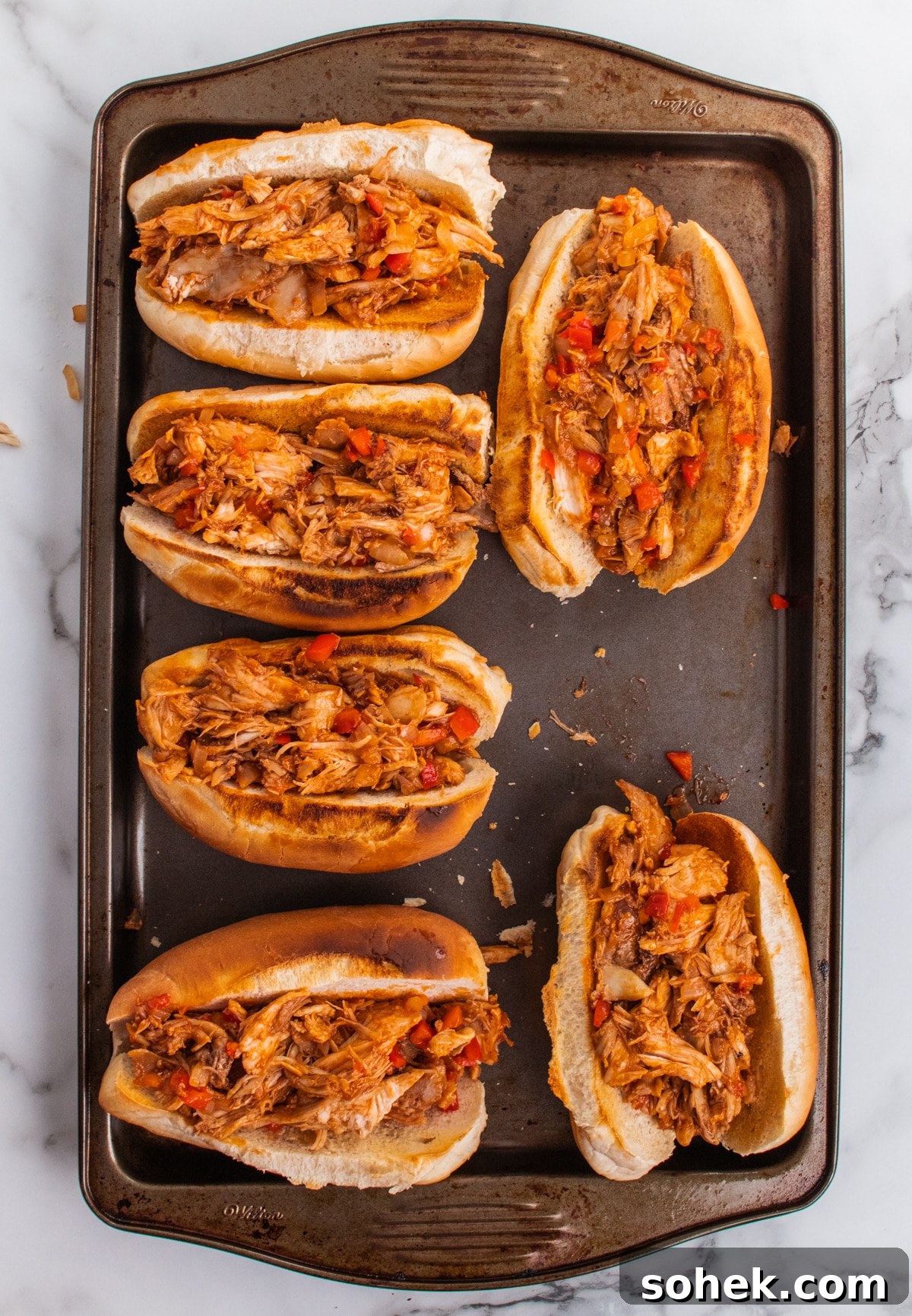 Leftover turkey meat stuffed into hoagie rolls on a baking sheet. 