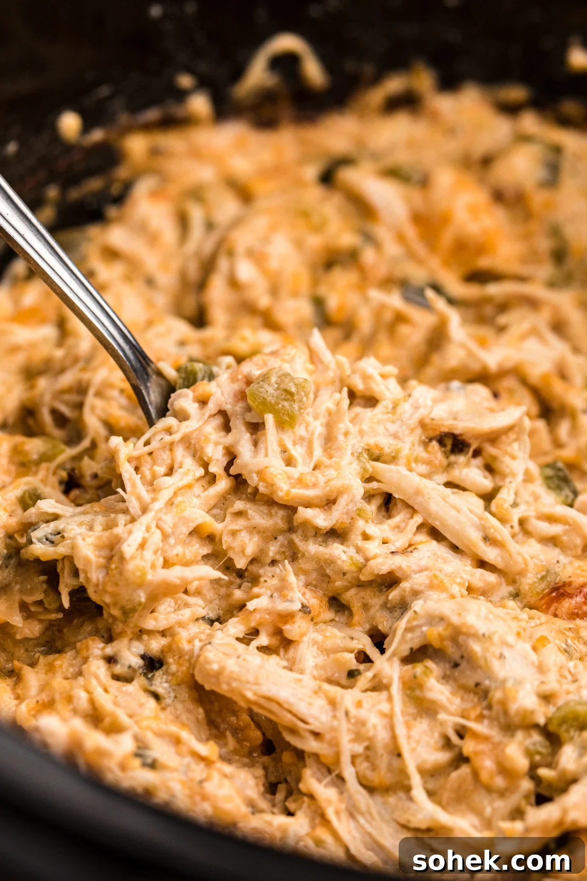 Slow Cooker Jalapeño Popper Chicken Recipe 2 jalapeno popper chicken in a slow cooker with a fork in it.
