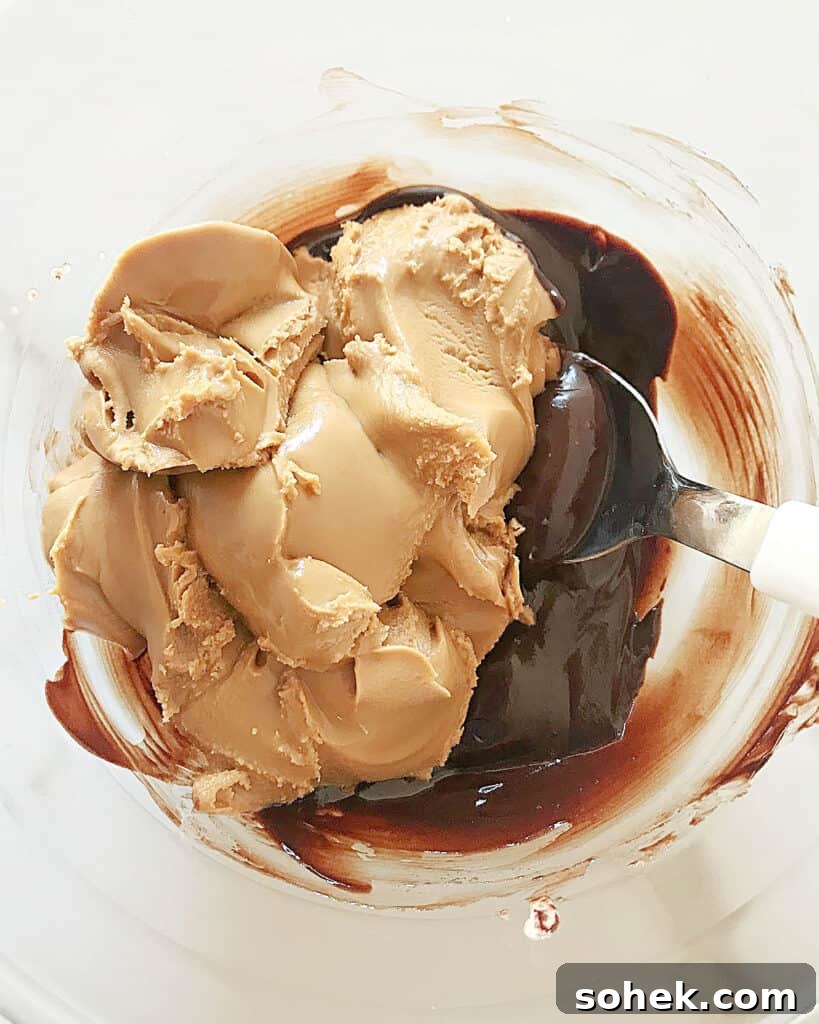 Decadent Chocolate Peanut Butter Frosting Recipe 3 Melted chocolate and peanut butter in a glass bowl. Spoon inside. Top view.