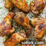 Baked dry rub chicken wings made with a brown sugar rub topped with finely chopped parsley on a sheet of parchment paper.