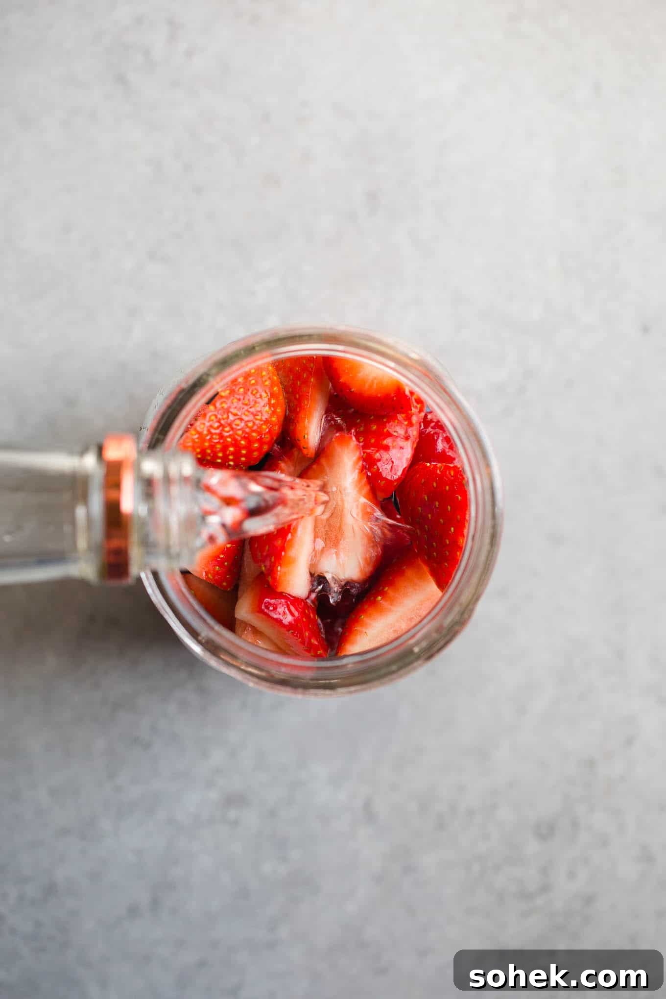 Pouring alcohol into a jar with berries.
