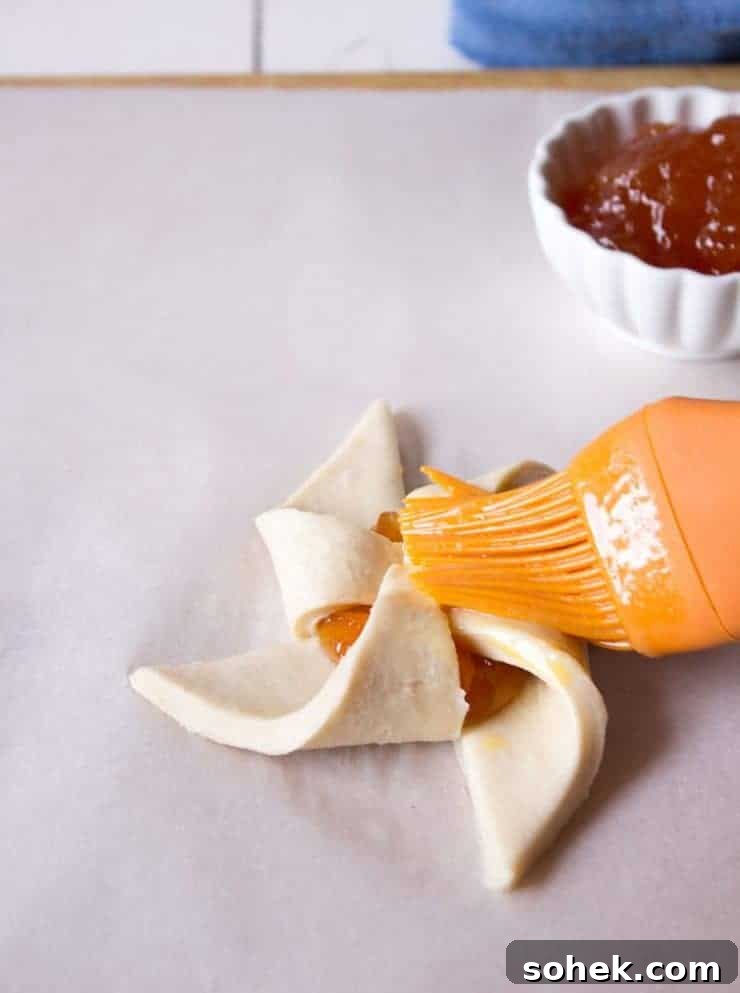 Savory and Sweet Puff Pastry Pinwheels: Quick Party Appetizers 5 Egg wash being brushed on a pastry.