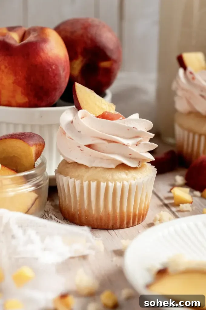 Gluten-Free Dairy-Free Peach Cupcakes: Moist Summer Dessert 2 Soft vanilla cupcakes filled with a peachy pink peach filling and topped with a fluffy light pink peach buttercream frosting swirl.