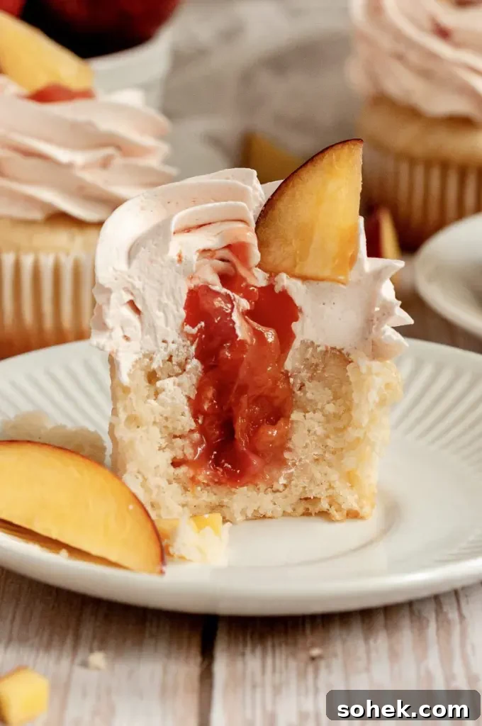 Gluten-Free Dairy-Free Peach Cupcakes: Moist Summer Dessert 5 Soft vanilla cupcakes filled with a peachy pink peach filling and topped with a fluffy light pink peach buttercream frosting swirl.