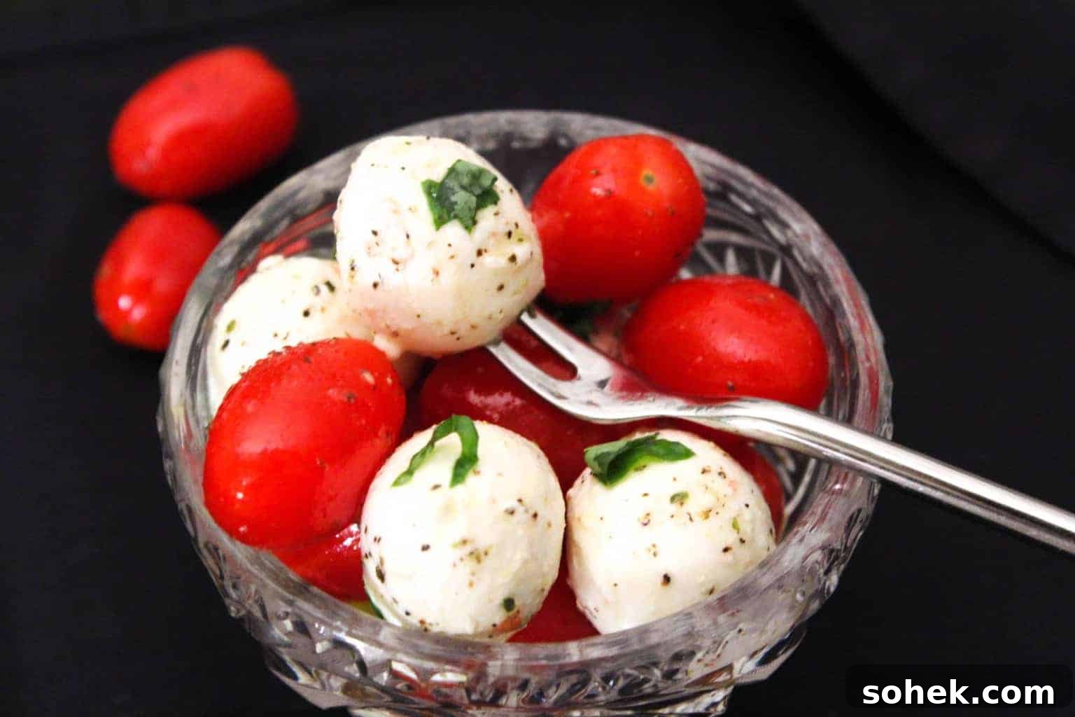Classic Caprese Salad Recipe with Fresh Mozzarella & Basil 2 Caprese Salad in glass bowl garnished with fresh basil.