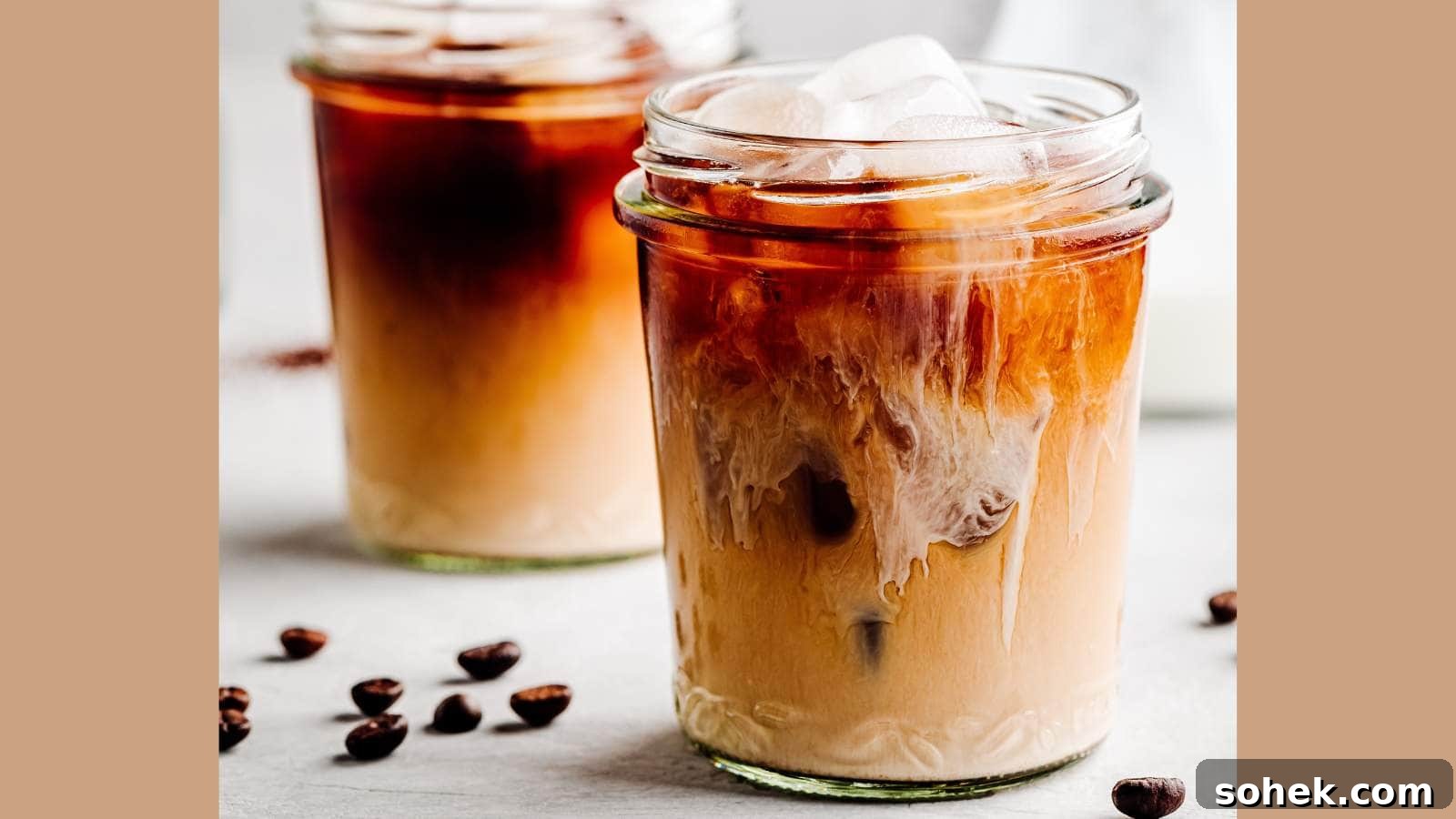 Two glasses of iced cold brew coffee with cream and coffee beans.