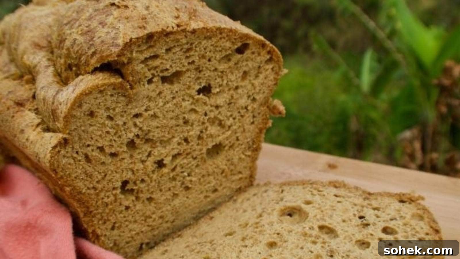 A close-up of a loaf of bread with a slice cut off, placed on a wooden surface.