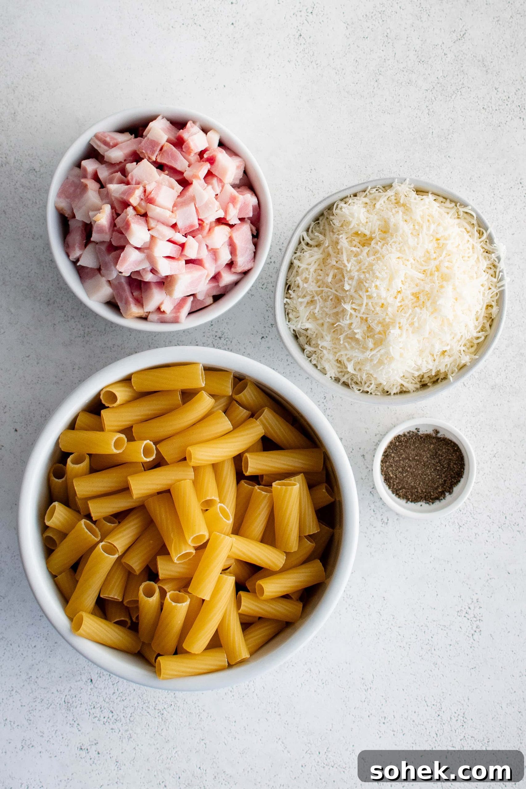 Ingredients needed to make pasta alla gricia recipe in a bowl in individual measuring cups and ramekins.