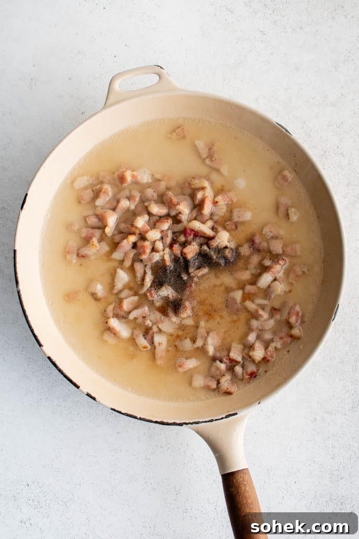 Pasta water added to a large pan filled with crispy cooked guanciale and rendered fat.