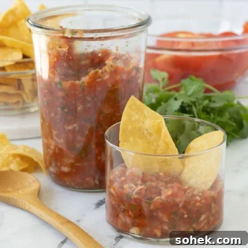 Smoked salsa in a tall jar and a small serving glass cup with corn chips