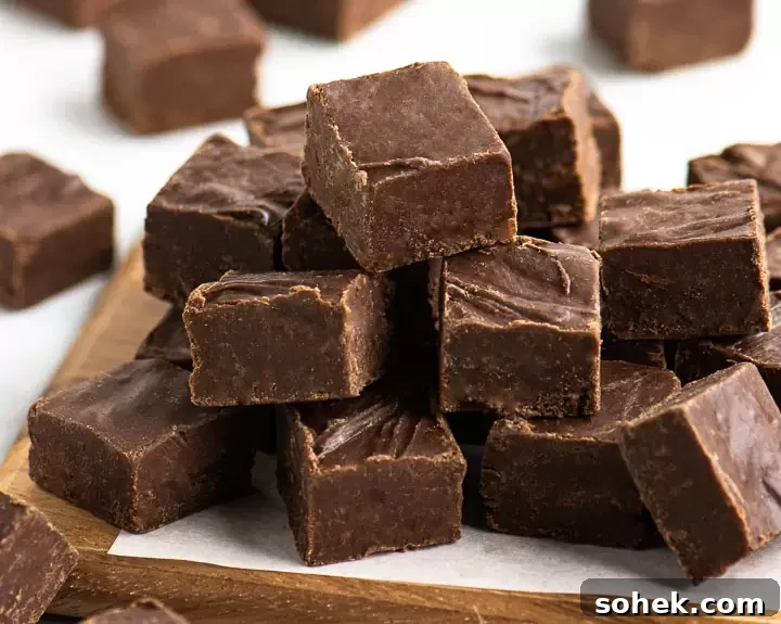 pieces of chocolate frosting fudge stacked on a wooden board