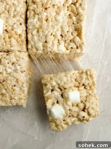 a close up of brown butter rice krispie treats with a marshmallow being pulled and stretched.
