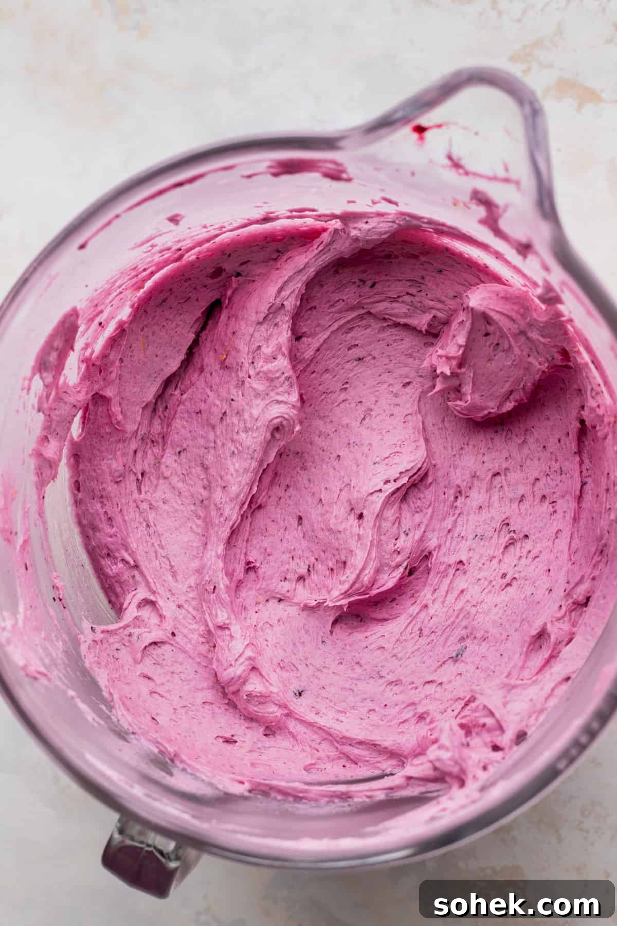 Blueberry frosting in a glass bowl.