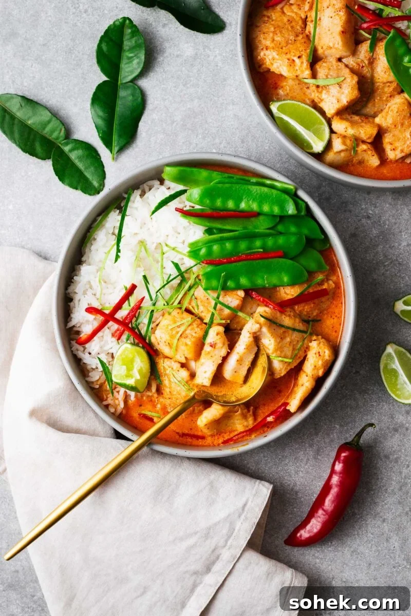 Spicy Thai Green Mango Salad (Yam Ma Muang) — Tangy Mango Thai Salad 15 A bowl with steamed jasmine rice, Thai fish red curry and snow peas topped with sliced red chile and kaffir lime leaves wit a golden serving spoon.